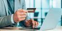 Person using a laptop with a credit card in an office setting