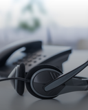 Black headset on a desk with a blurred office background