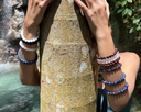 Person wearing multiple EEBracelets on a stone surface with water in the background