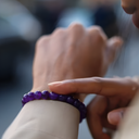 Close-up of a hand wearing EEBracelet Amethyst with a blurred background