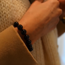 Close-up of a hand wearing EEBracelet Black Onyx against a blurred background