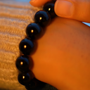 EEBracelet Black Onyx being held by a hand with a blurred background