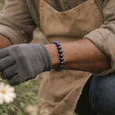 Person wearing EEBracelet Hawk Eye and gray glove in a natural setting with flowers.