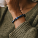 Close-up of a wrist wearing EEBracelet Hawk Eye with a green sweater sleeve.