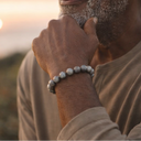 Man with a beard and EEBracelet Labradorite sitting outdoors with a sunset in the background