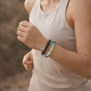 Person wearing a white tank top and EEBracelet Onyx Agate Duo on a blurred natural background