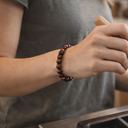 Person wearing EEBracelet Red Tiger's Eye on wrist with blurred background