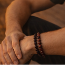 Close-up of a person's arm wearing EEBracelet Red Tiger's Eye with a blurred background