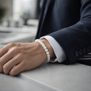 Person wearing a dark suit with a white shirt and EEBracelet White Jade, sitting at a desk.