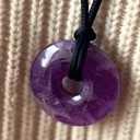 EEMedallion Amethyst on a black cord against a beige knitted background