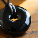 EEMedallion Black Obsidian on a wooden surface.