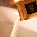Gold packet of EESystem salts being poured onto a white surface