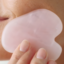 Close-up of Gua Sha Rose Quartz being held by a hand.